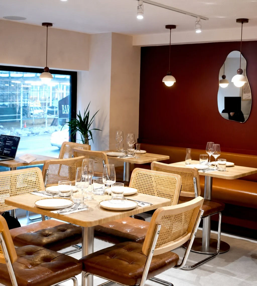 Tables set with wine glasses beneath pendant lights