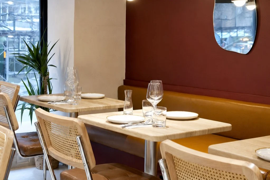 Burgundy wall, organic mirror and cane chairs inside Aromati
